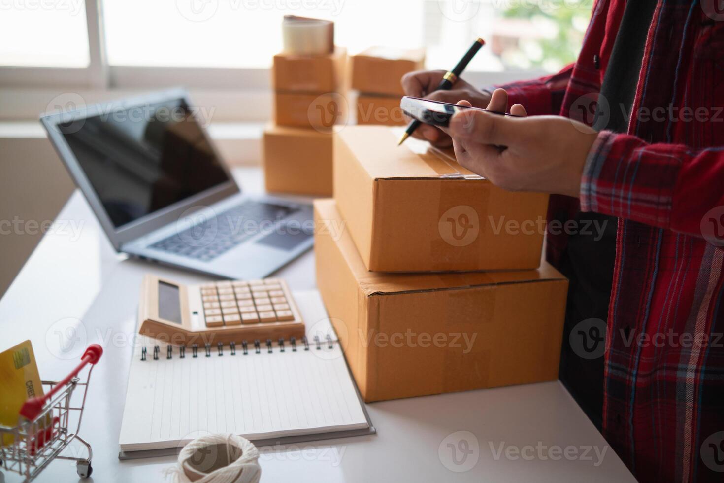 A man is using a calculator and a pen to write on a piece of paper photo