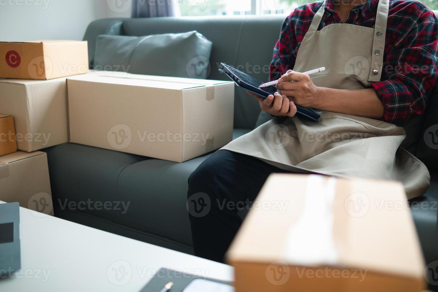 A man in an apron is sitting on a couch with boxes photo