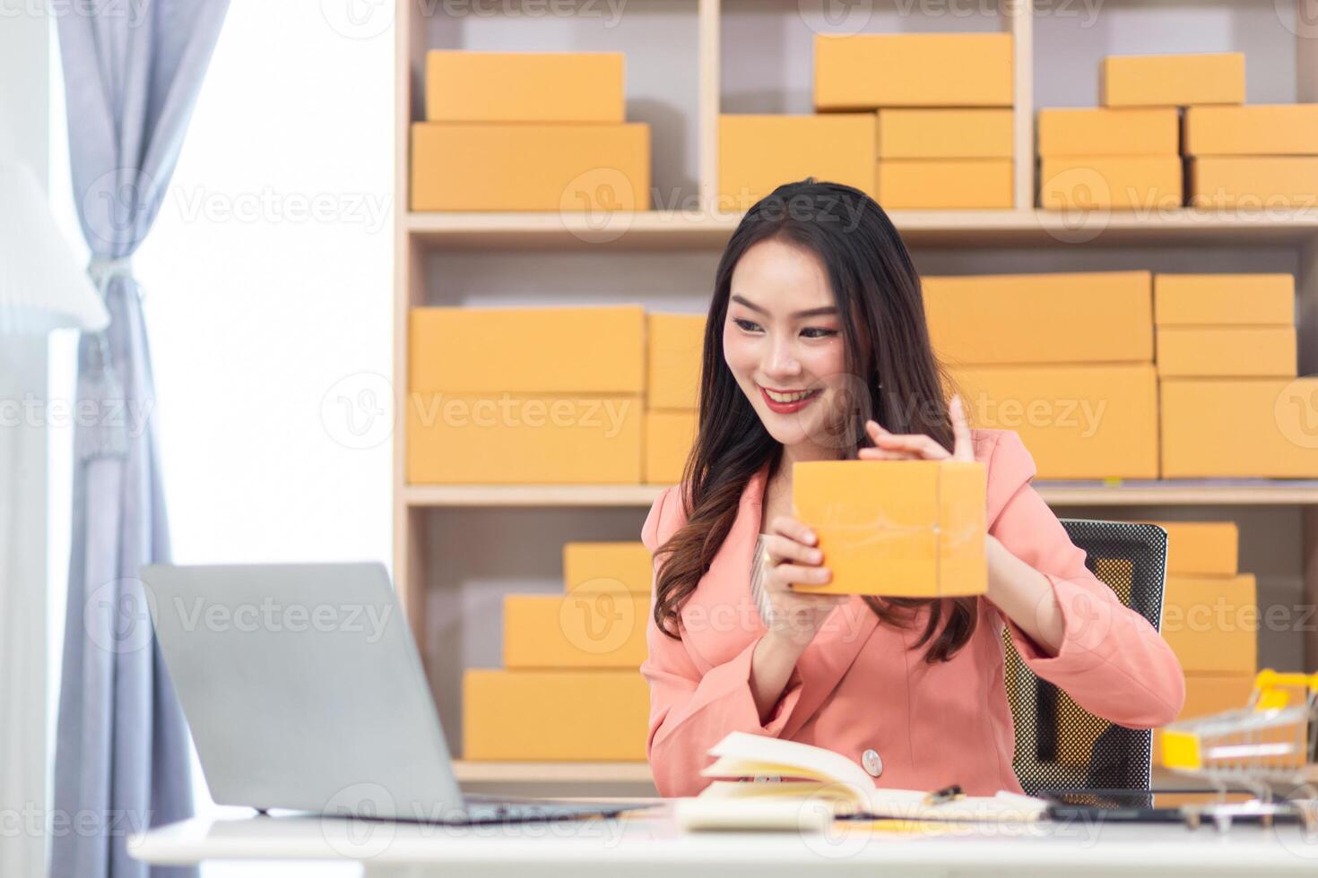 Asian woman in office with laptop and yellow box photo