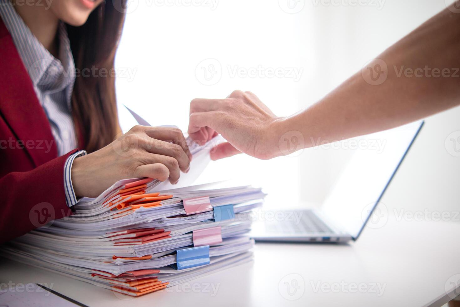 A woman in a red suit holding a stack of papers photo