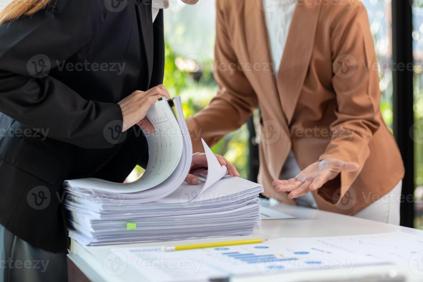 Two businesswomen are working on paperwork at a desk photo