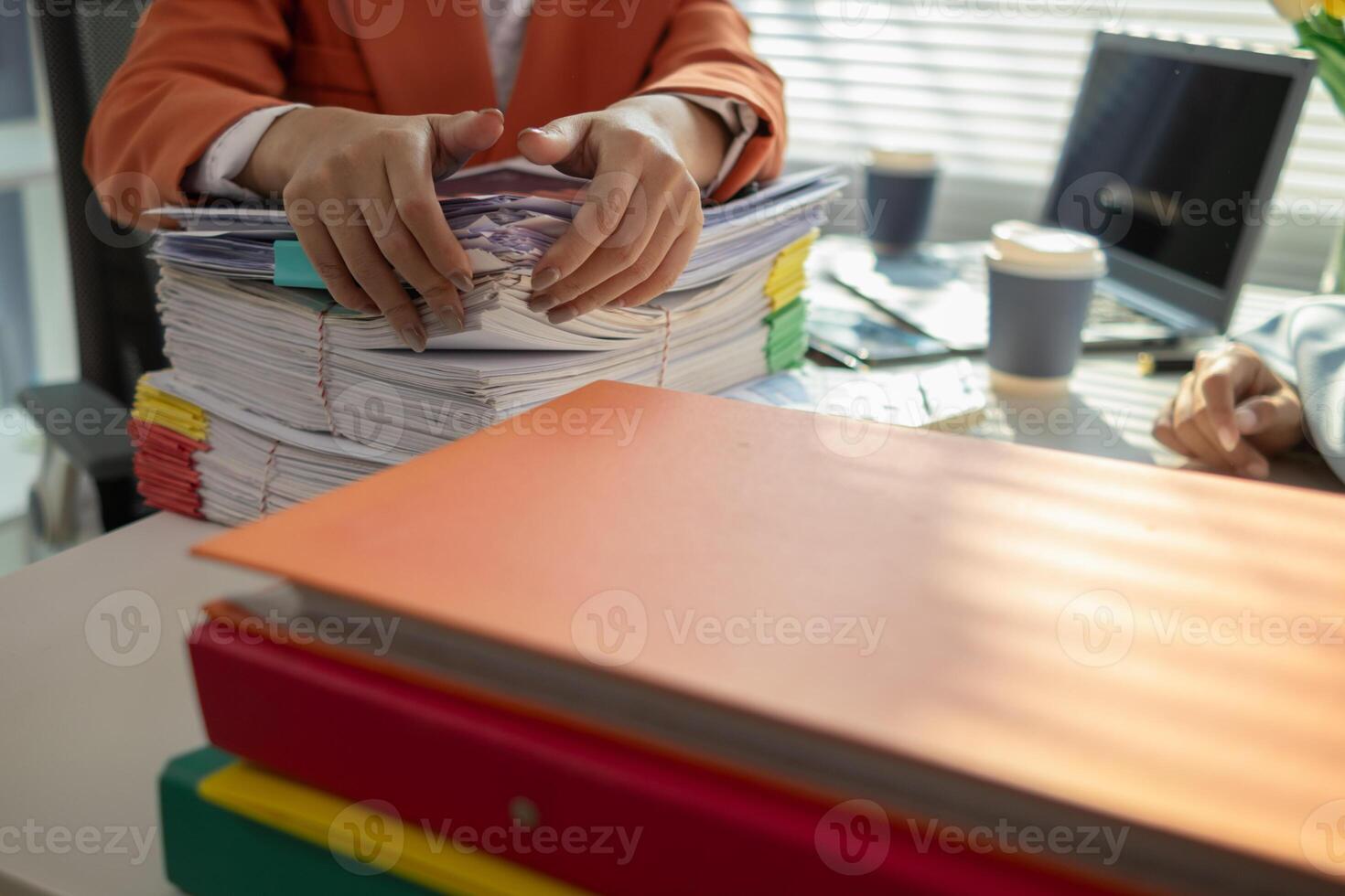 A person is sitting at a desk with stacks of papers photo