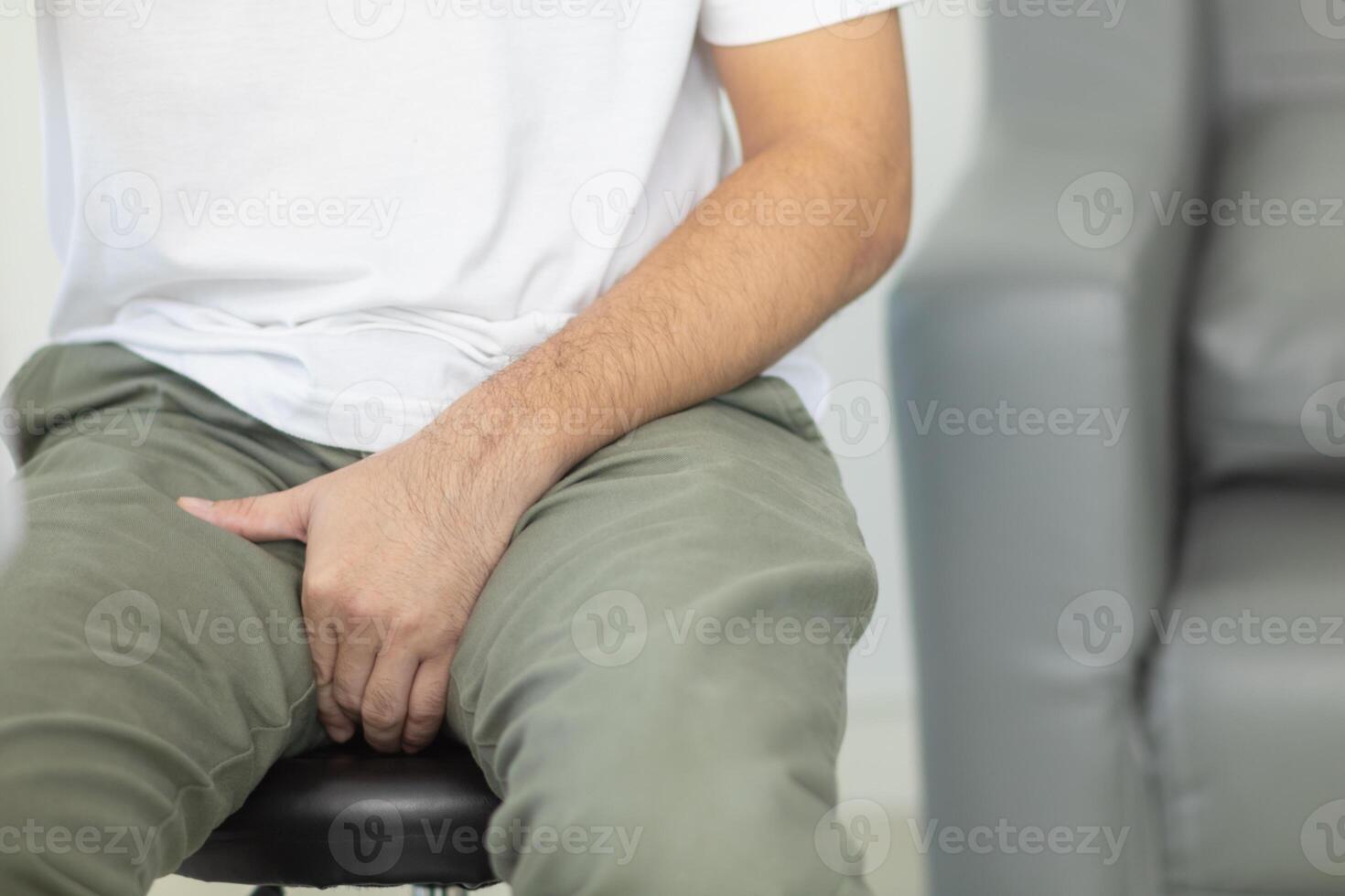 A man sitting on a stool with his hands on his stomach photo
