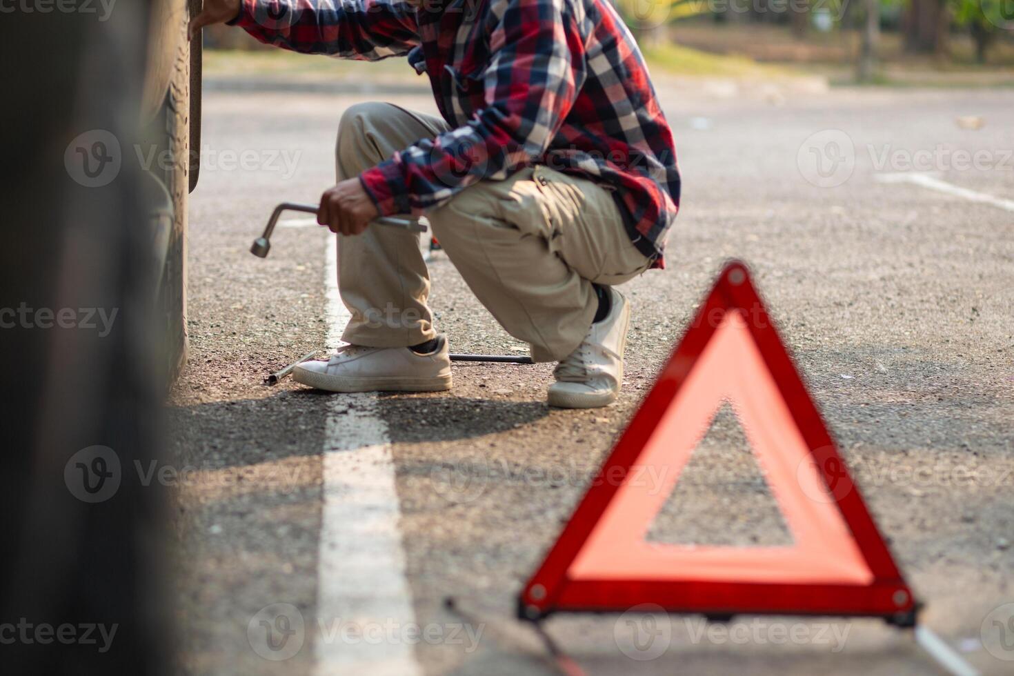 A man fixing a car tire with a wrench photo