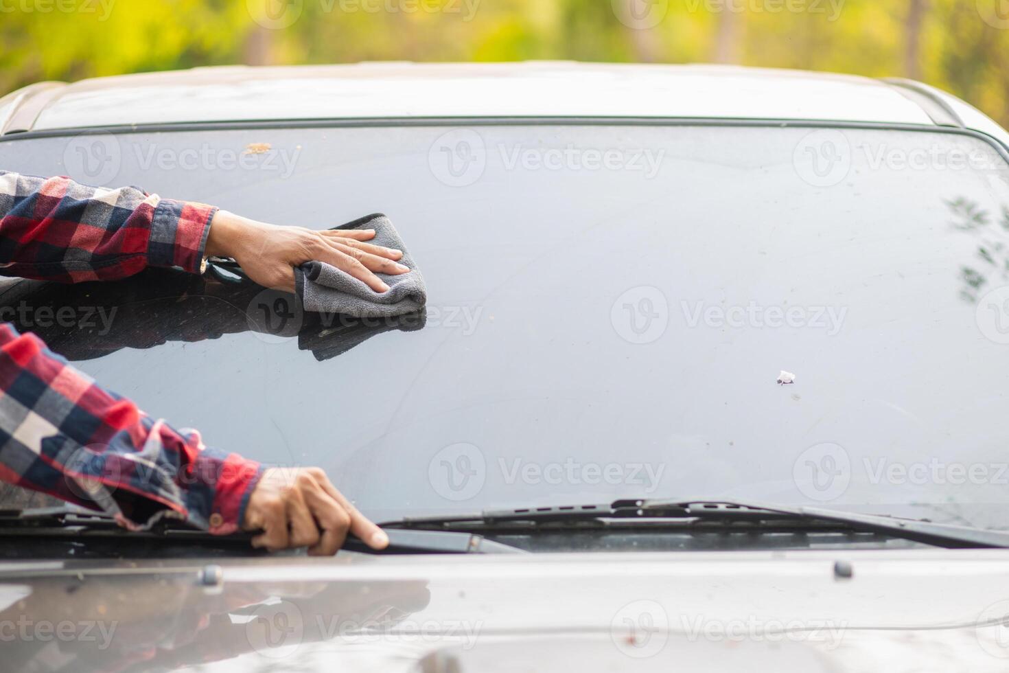 Man cleaning windshield of car with cloth photo