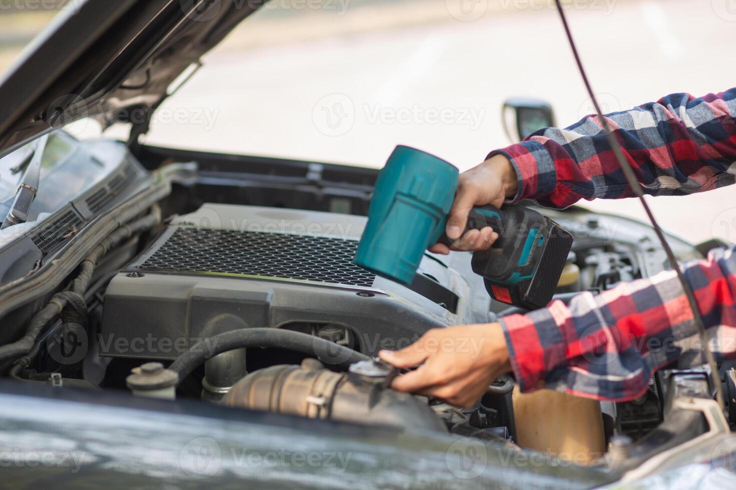 A man is using a tool to clean the engine of a car photo