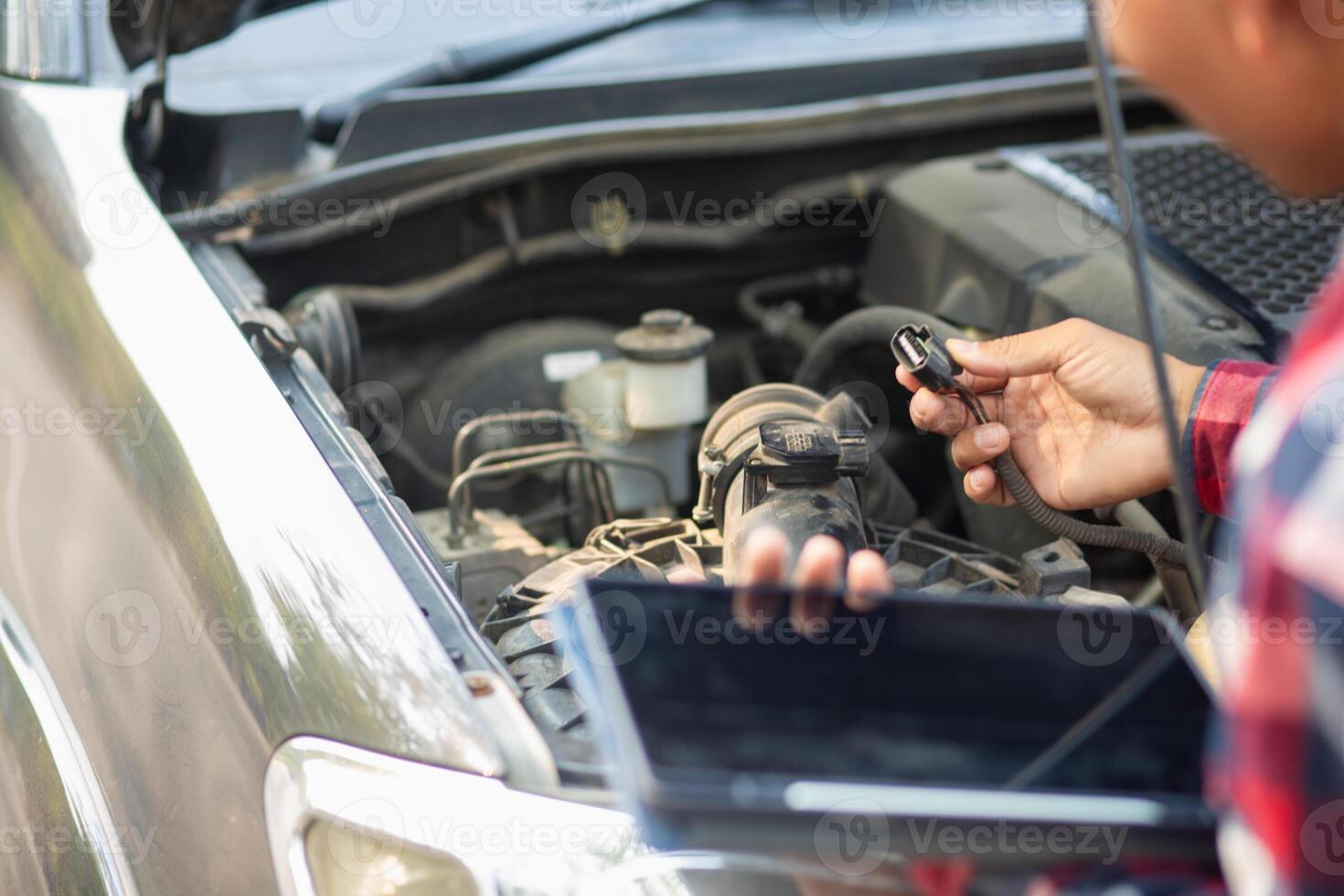 A man is using a tablet to check the engine of his car photo