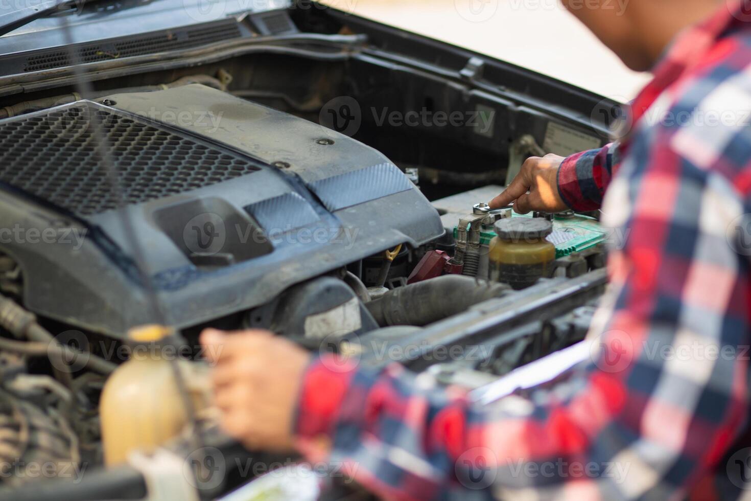A man is checking the engine of a car photo
