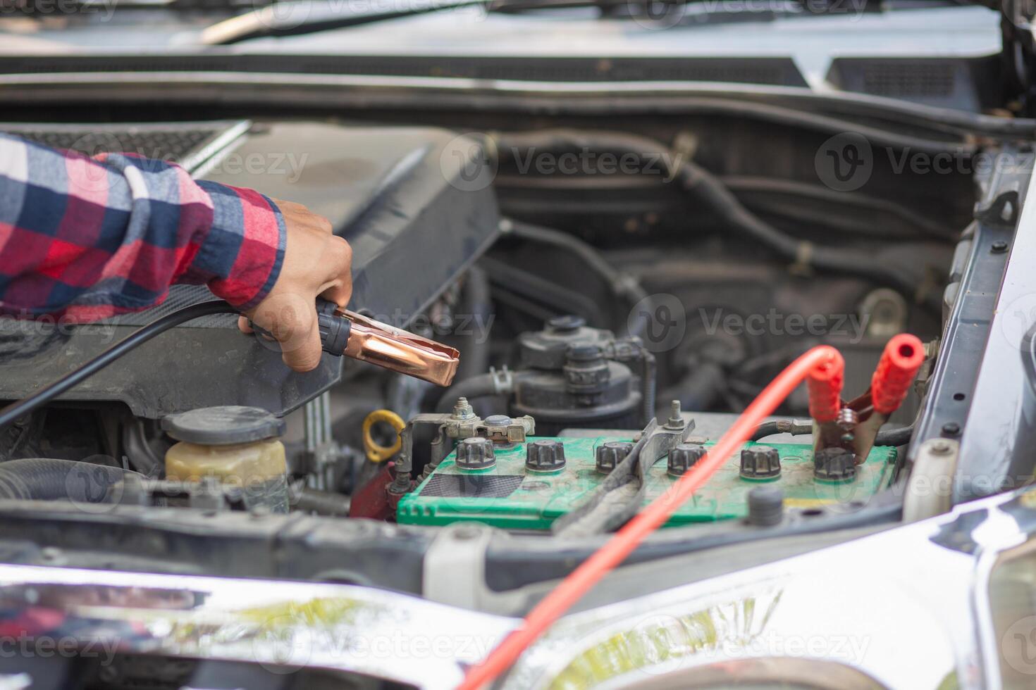 A man is using an electric tool to check the battery in a car photo