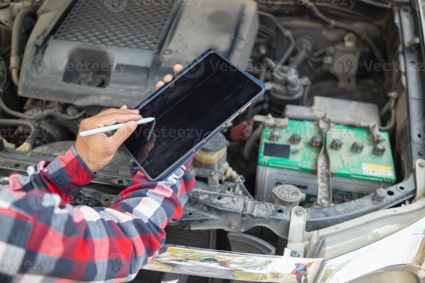 A man is holding a tablet while looking at his car photo