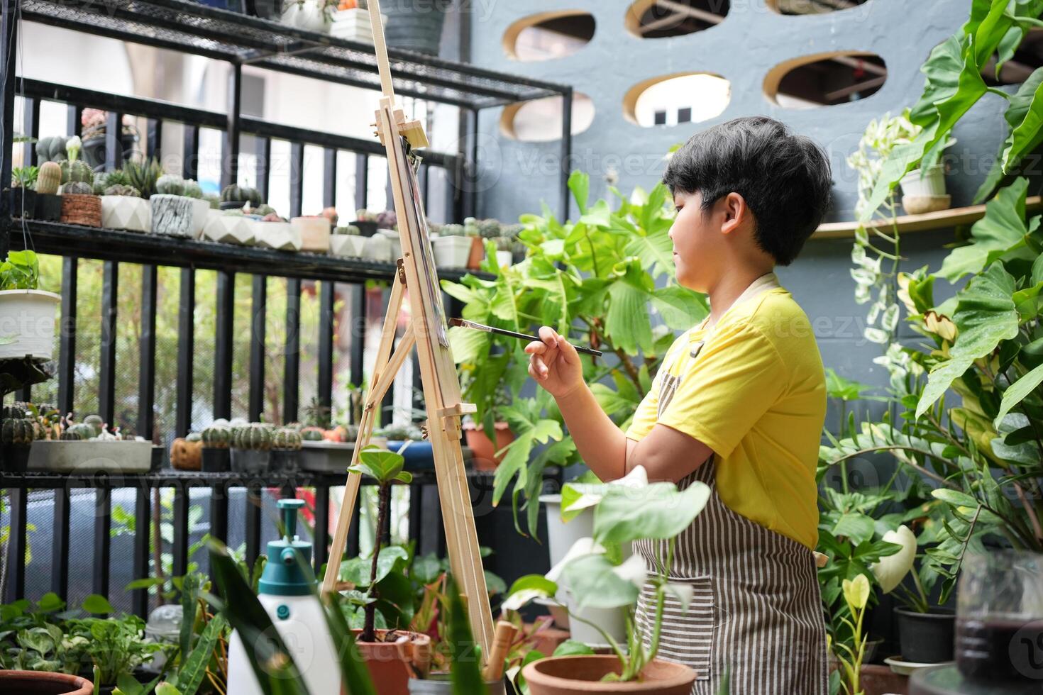 Boy Painting on Easel in Garden at Home, Asian Kid Artist Drawing with Colorful Paints at Home photo