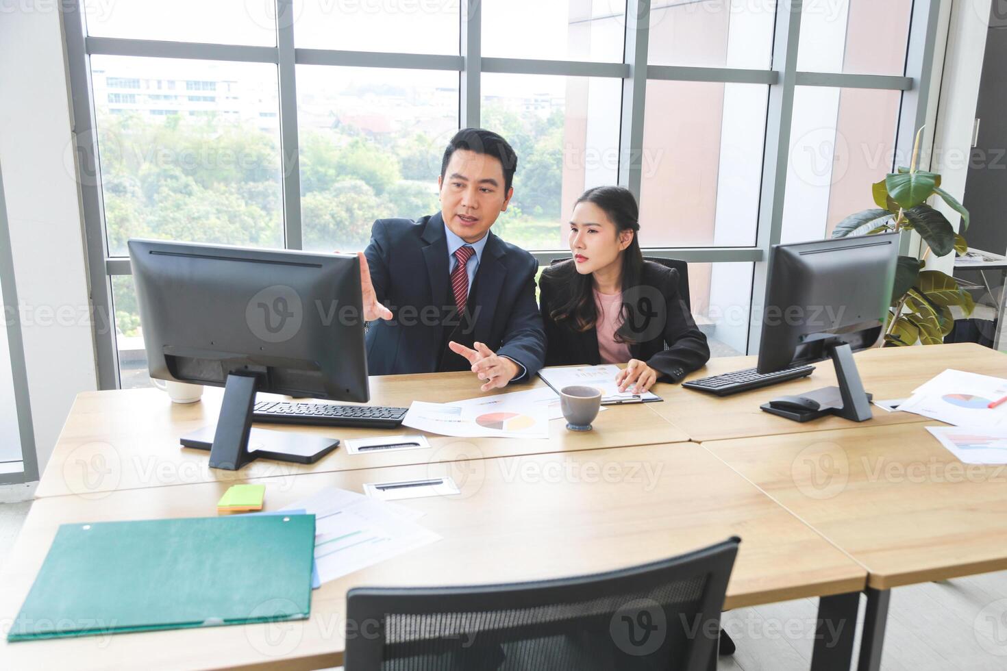 Business colleagues discussing data at desk, Asian professional business meeting in office, Supervisor training and suggesting about work to colleagues, Businesspeople team meeting in modern office photo