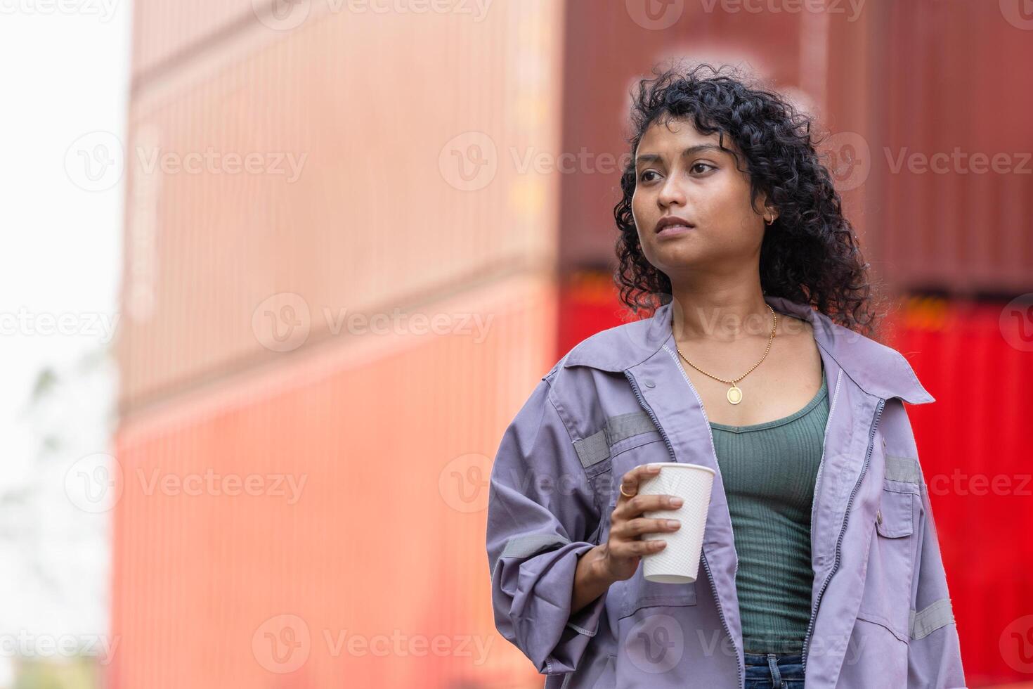 Foreman worker with coffee cup in industry containers cargo, Female engineer taking a break in shipping container yard photo