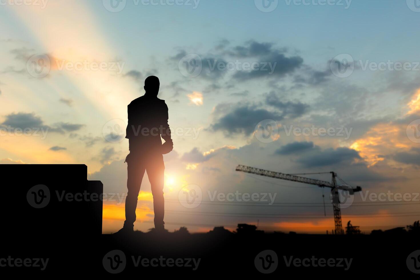 Silhouette of Engineer on building site, construction site at sunset in evening time photo