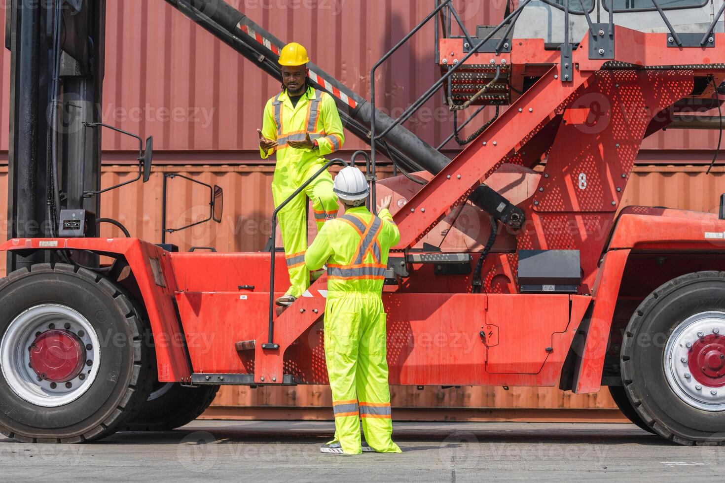 Dock Workers Discussing Operations Near Cargo Handler, Industrial Workers in Safety Gear at Container Terminal, Heavy Equipment Operators Communicating at Shipping Port photo