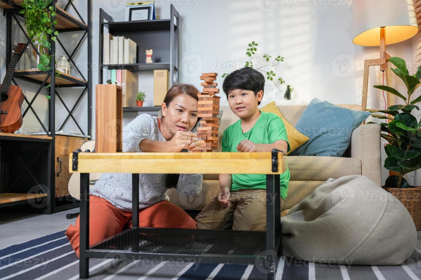 Mother and Son Playing Block Game in Living Room, Happy Asian Family Bonding with Fun Indoor Game, Parent and Child Enjoying Quality Time Together photo