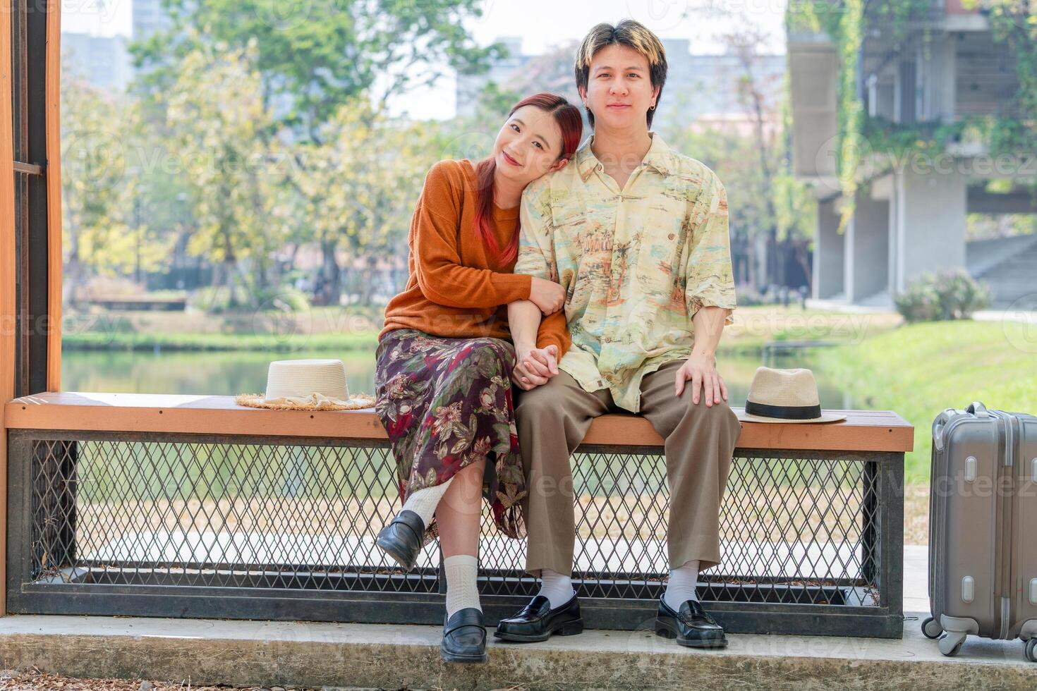 Couple Resting in Park on a Sunny Day, Joyful Young Asian People Dating in a Green Park Setting, Affectionate Couple Traveling and Sitting on Bench photo