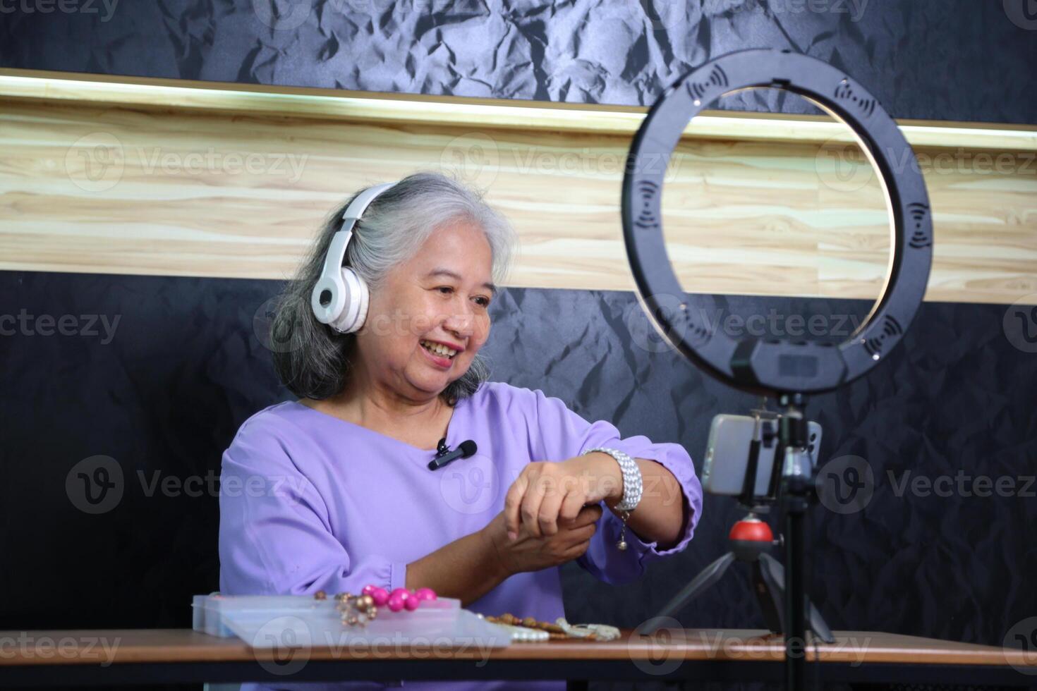 Senior Woman Creating Online Content Live Streaming or Vlogging from Home, Mature Woman Using Technology for Online Sales or Social Media Engagement photo