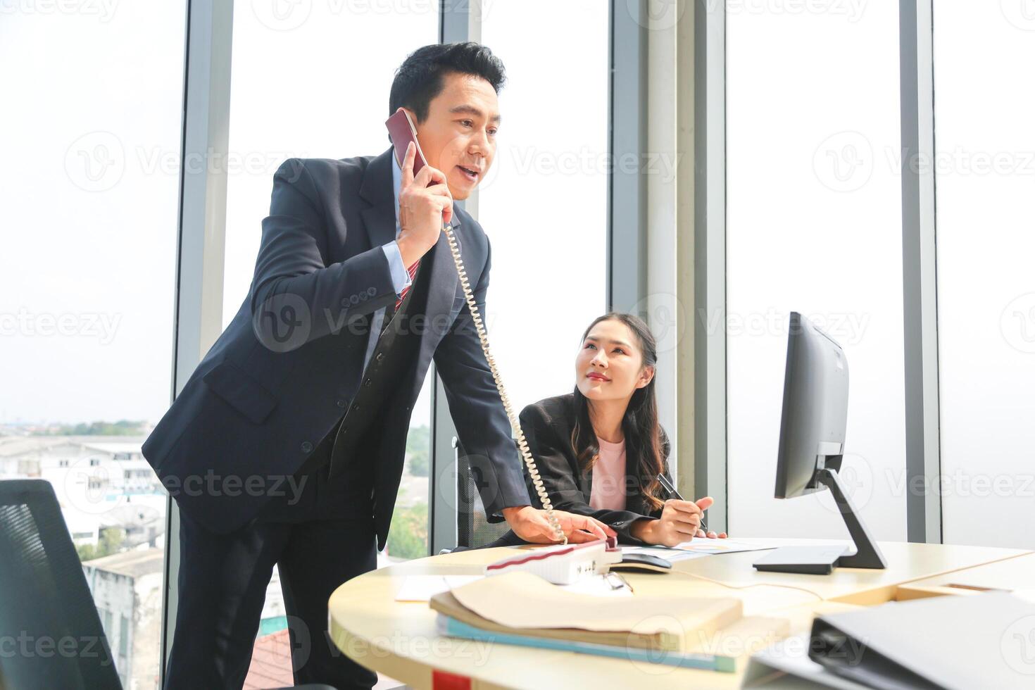 Businessman on Call with Female Colleague in Modern Office, Asian Business Professionals Working Together in an Office photo