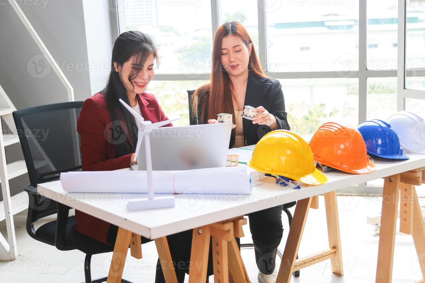 Smiling Female Architects Collaborating on Sustainable Design, Young Asian Engineers Discussing Building Plans and Green Energy, Professional Women Working on Architectural Project photo