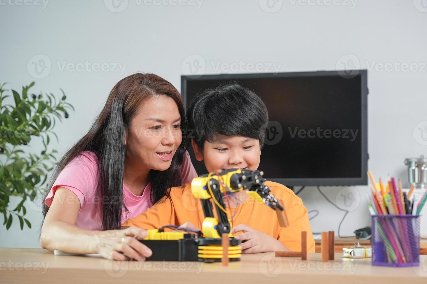 Mother and Son Learning Robotics Together, Young Boy Engaged in STEM Education with Robot Arm photo