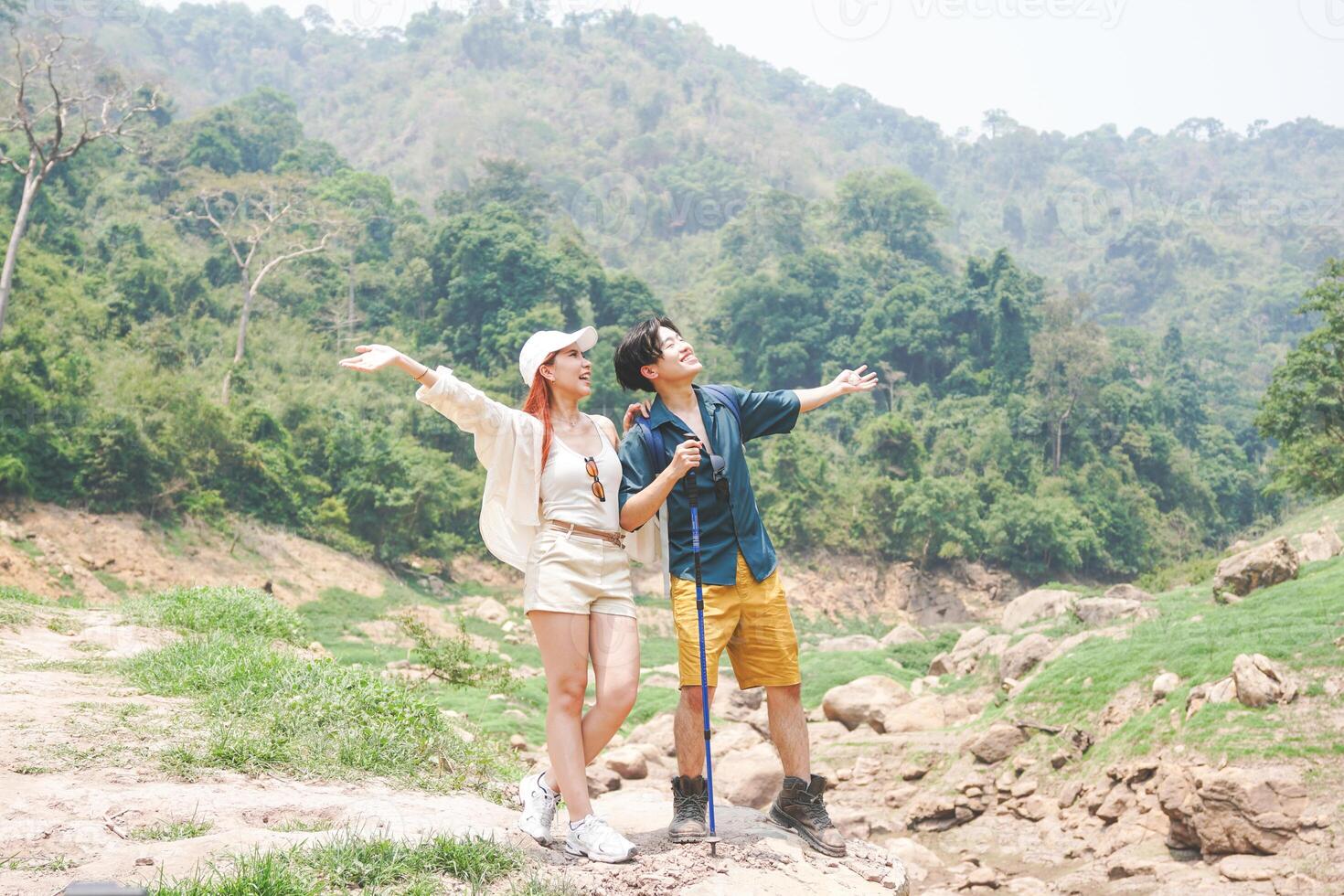 Young Hikers with Arms Outstretched in Nature, Happy Travelers Exploring Lush Green Mountains, Joyful Couple Enjoying a Scenic Outdoor Adventure photo