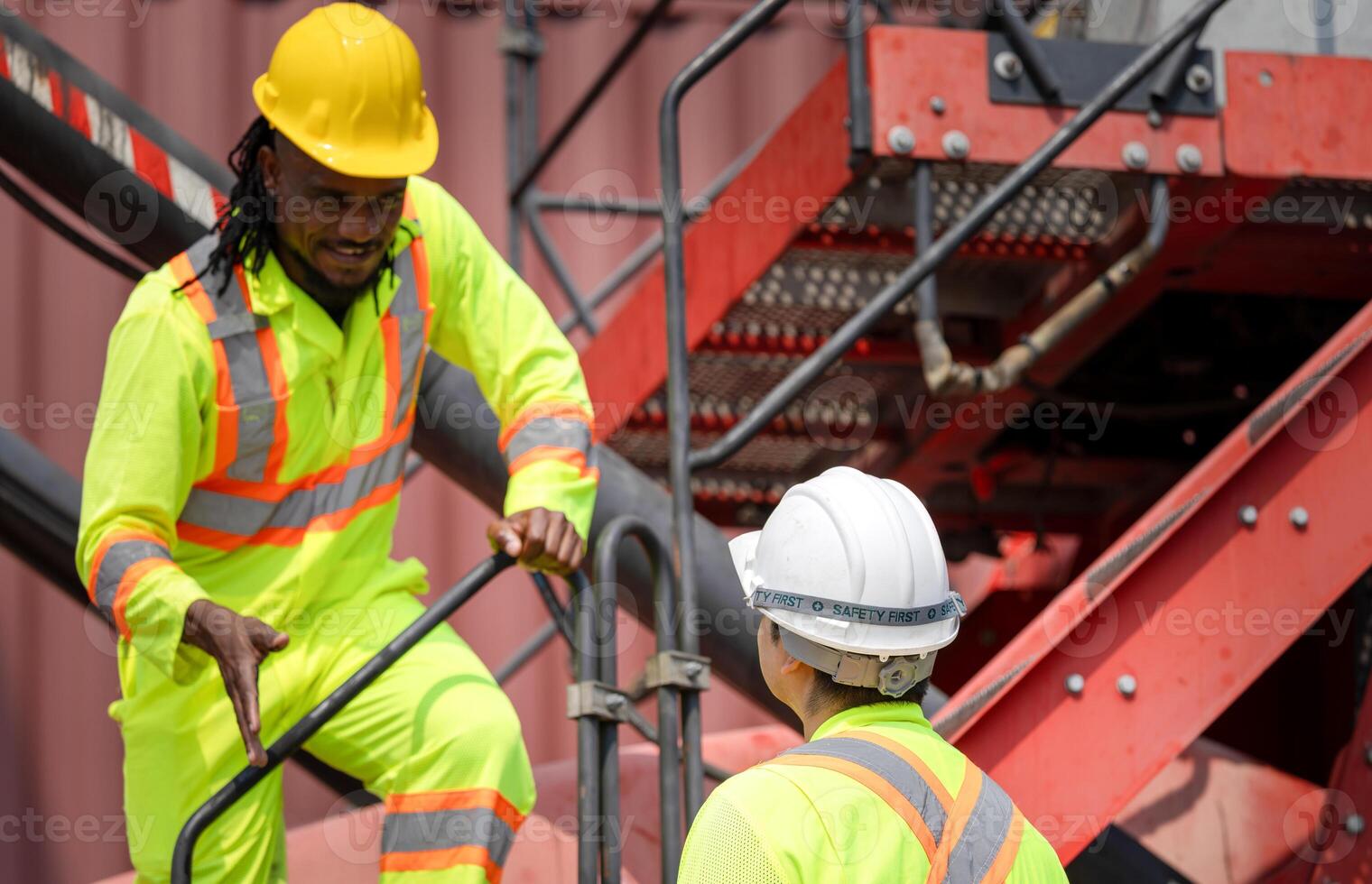 Diverse Team of Engineers Working in Industrial Shipping Yard, Construction Workers Discussing Project on Metal Stairway, Industrial Workers in High Visibility Gear at Construction Site photo
