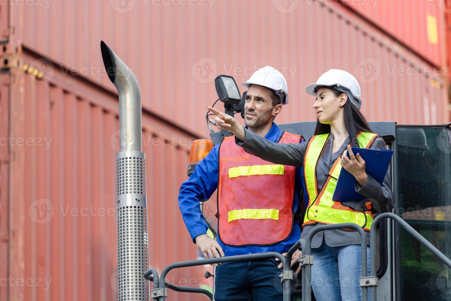 Engineer and foreman worker inspecting containers box at shipping yard, Inspectors standing on top of a container handlers machine at container yard photo