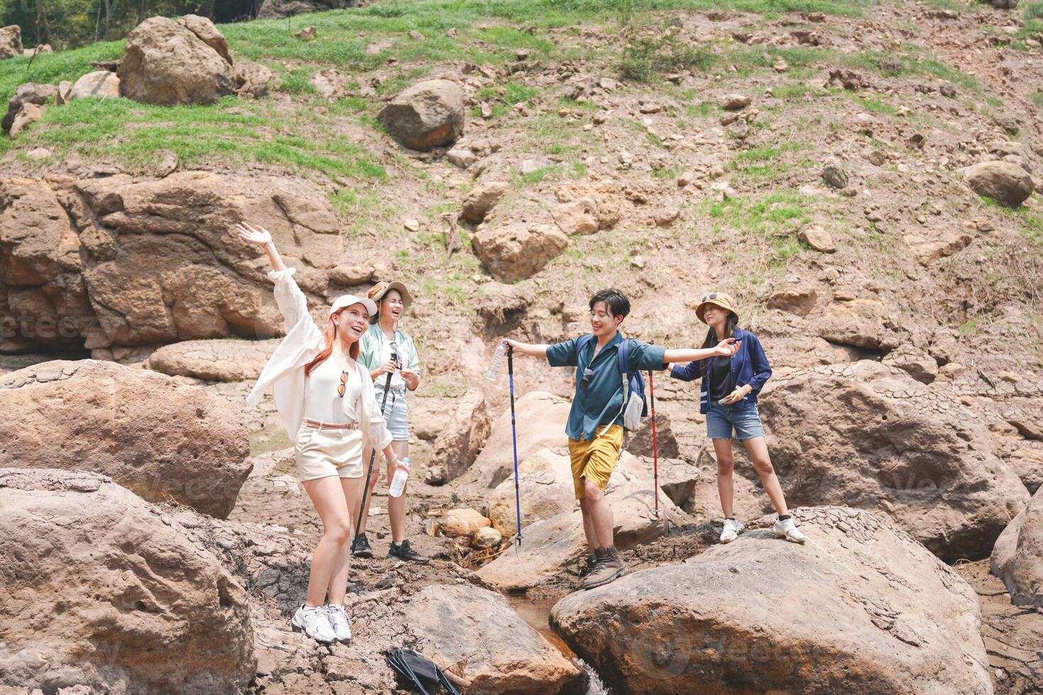 Group of Friends Enjoying a Fun Hike on Rocky Terrain, Happy Hikers Posing and Waving in a Natural Landscape, Young People Exploring Outdoors on a Summer Adventure photo