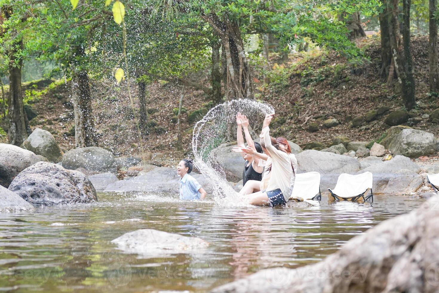 Group of Friends Enjoying a Refreshing Dip in a Natural Forest River, Young Adults Splashing in a Clear Stream Outdoors, People Having Fun in Nature photo