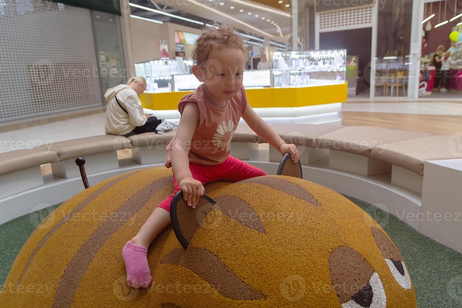 Curly-haired child of three plays in a play center. People photo