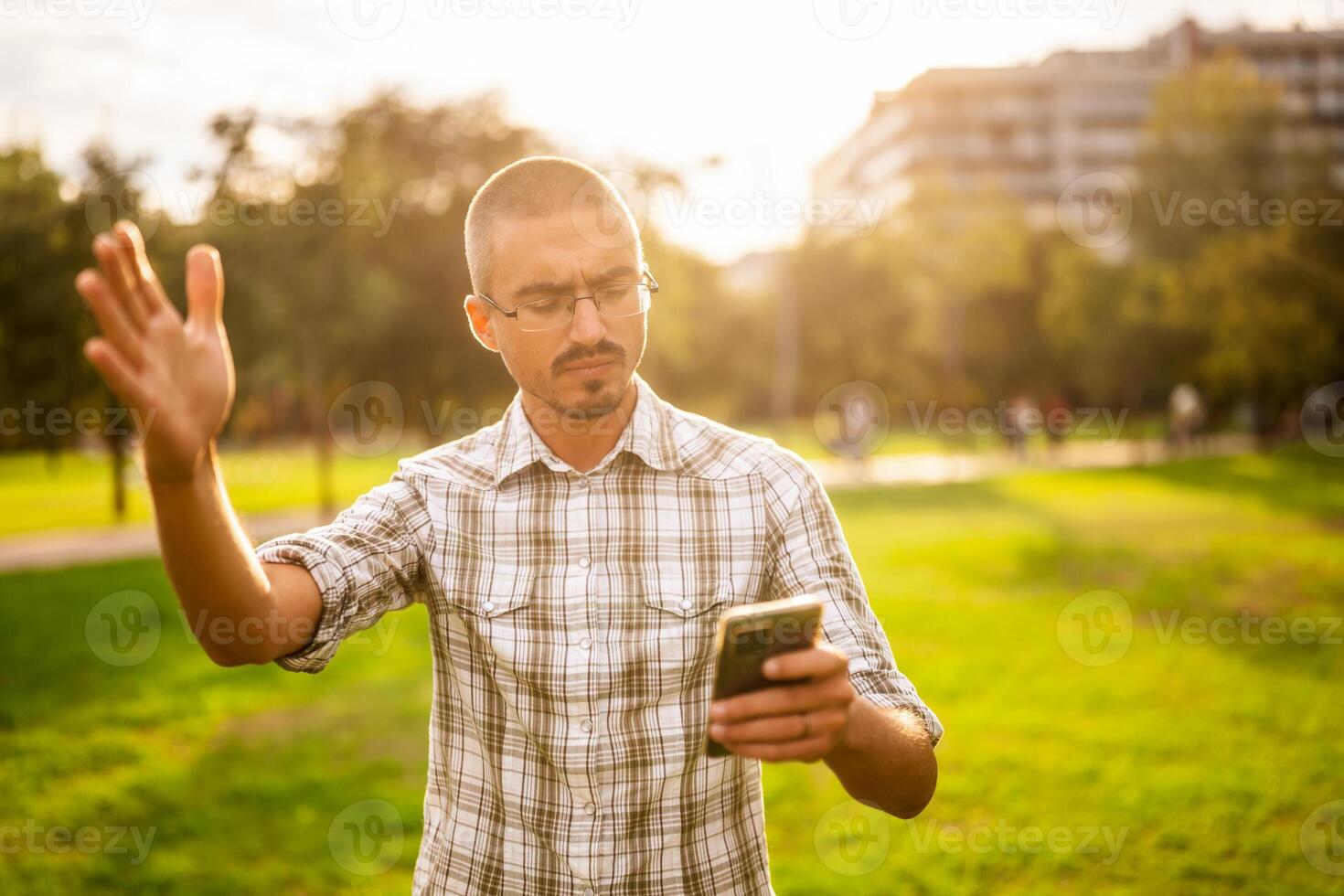 Angry man in park. He is using smartphone photo