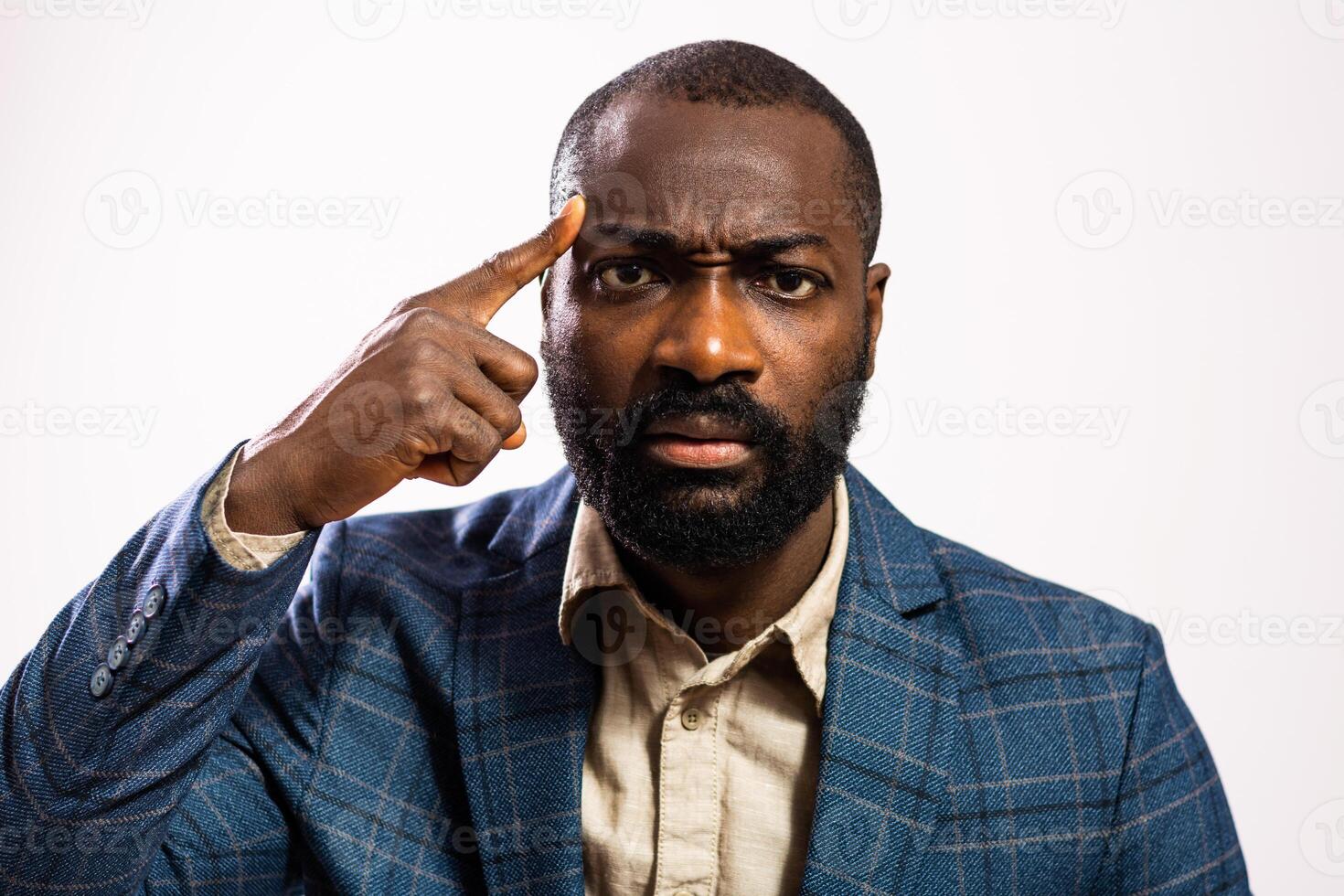Close up of portrait of thoughtful black male manager contemplating ideas with a focused gaze and hand pointing to his head. photo