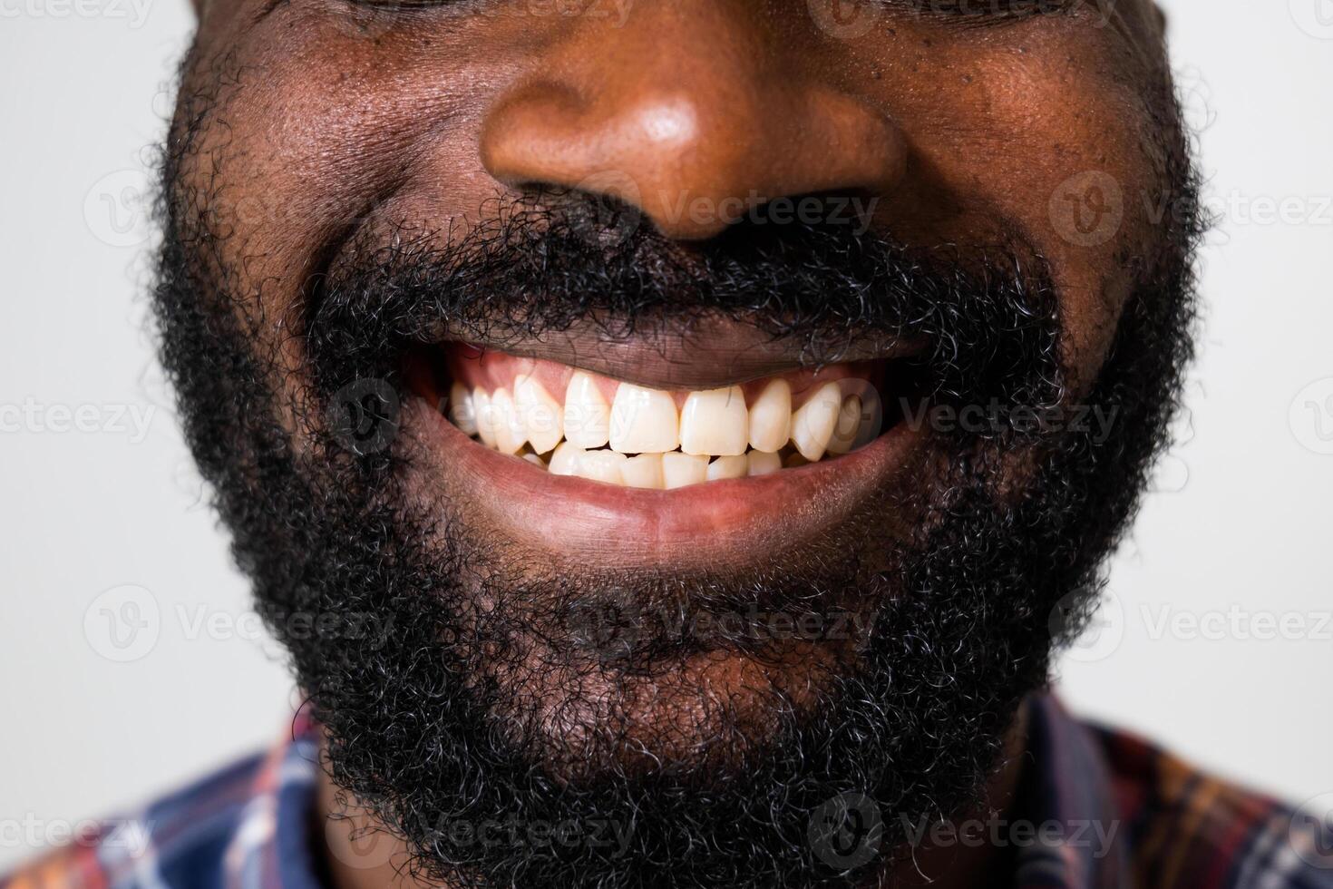 Close up portrait of perfect white teeth of a cheerful African American man smiling confidently on the gray background. photo