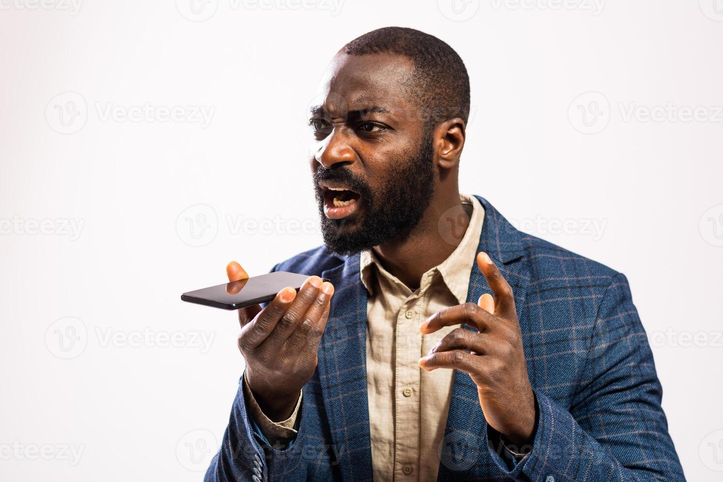 Angry African American man in business attire expressing displeasure while talking on his mobile phone. photo
