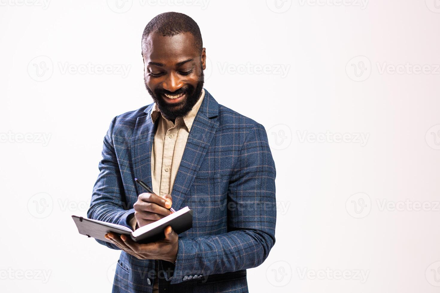 Portrait of confident African American businessman in suit organizes tasks on his notepad. Studio shot on the gray background. photo