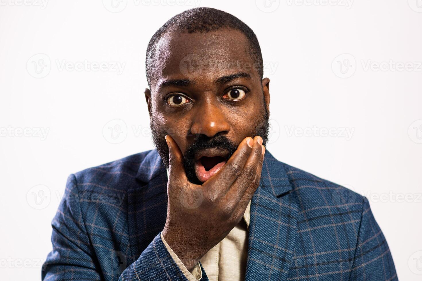 Close up portrait of African businessman looking directly at the camera with hand on chin and showing signs of worry and surprise. photo