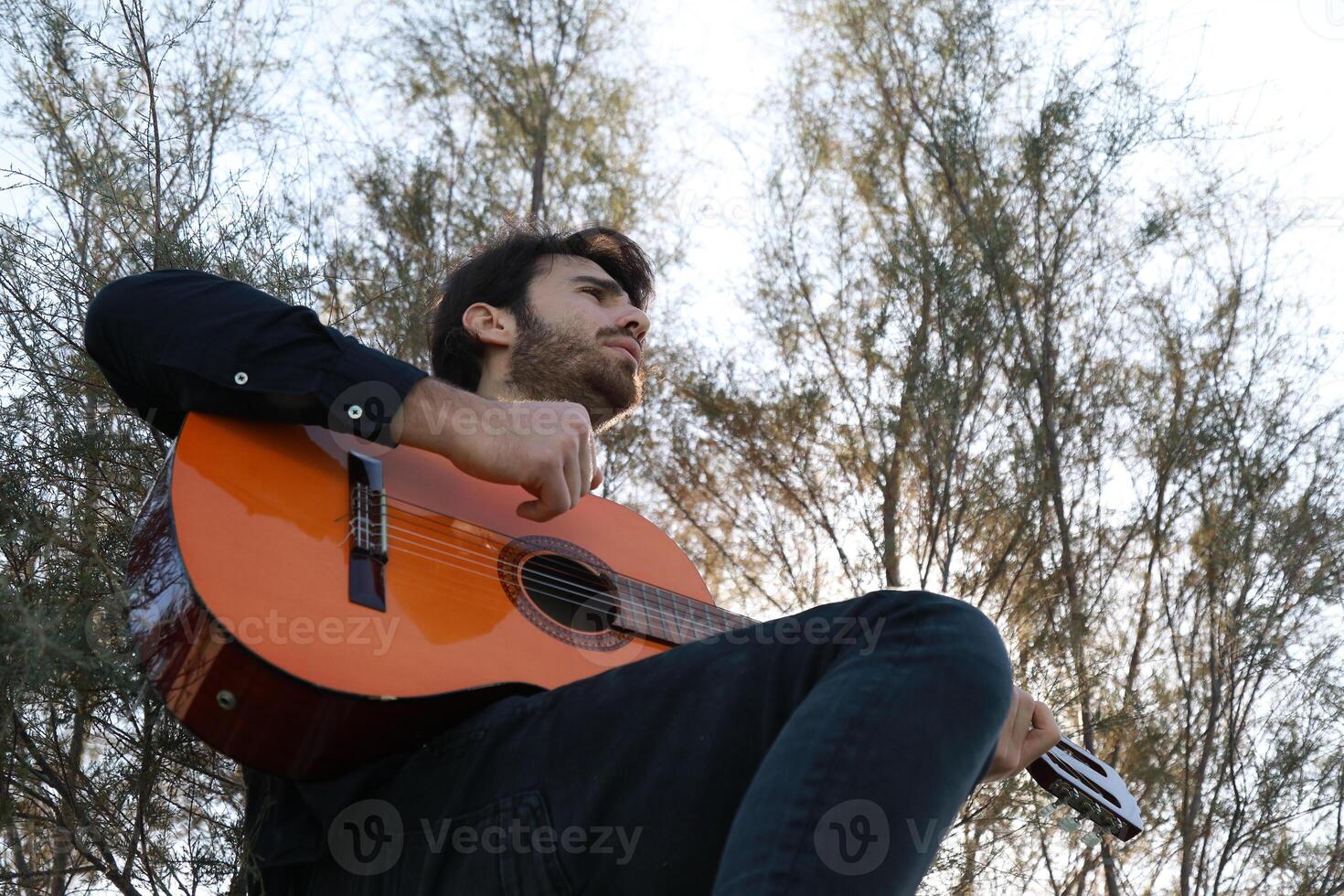Player Delights In Chords With The Guitar And Stands Before Concert Outdoor photo