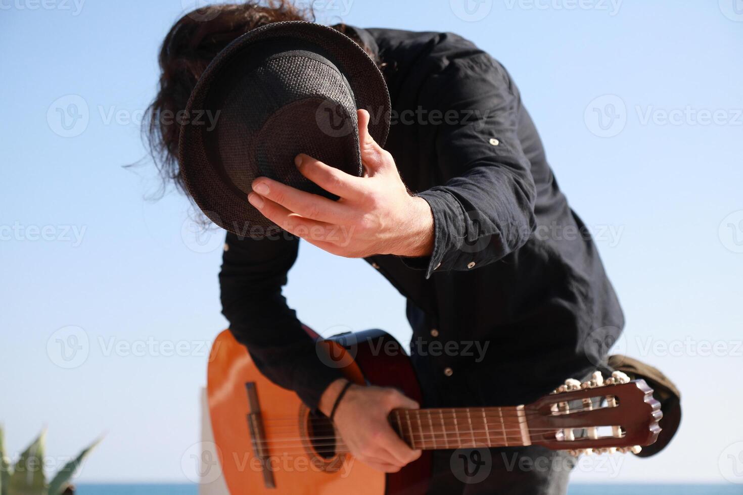 Street Artist Takes a Bow After Playing Classical Guitar on the Beach Outdoor Near Ocean photo