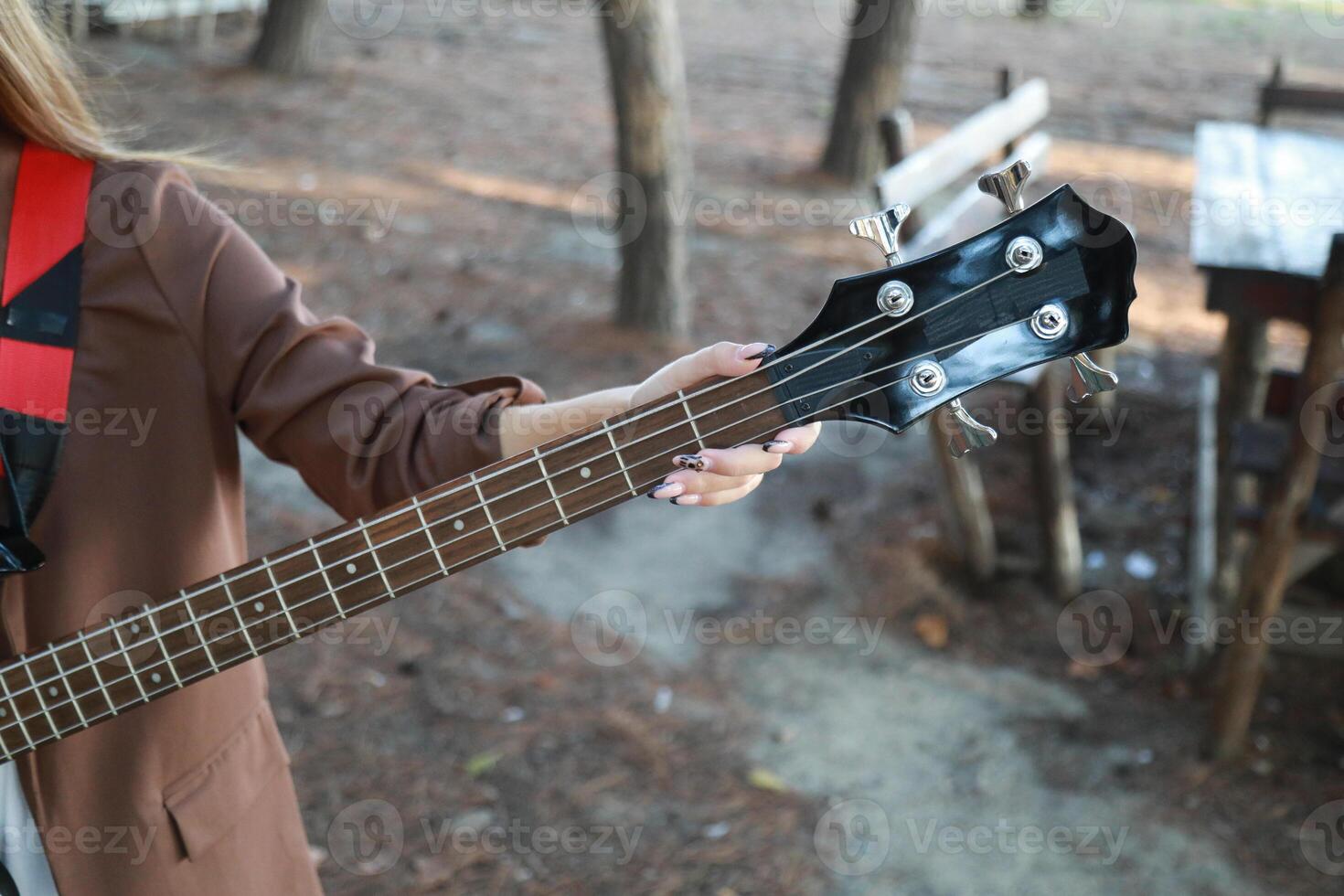 Girl Plays Bass Musical Instrument Under Trees Outdoor In Mountain Outdoor photo