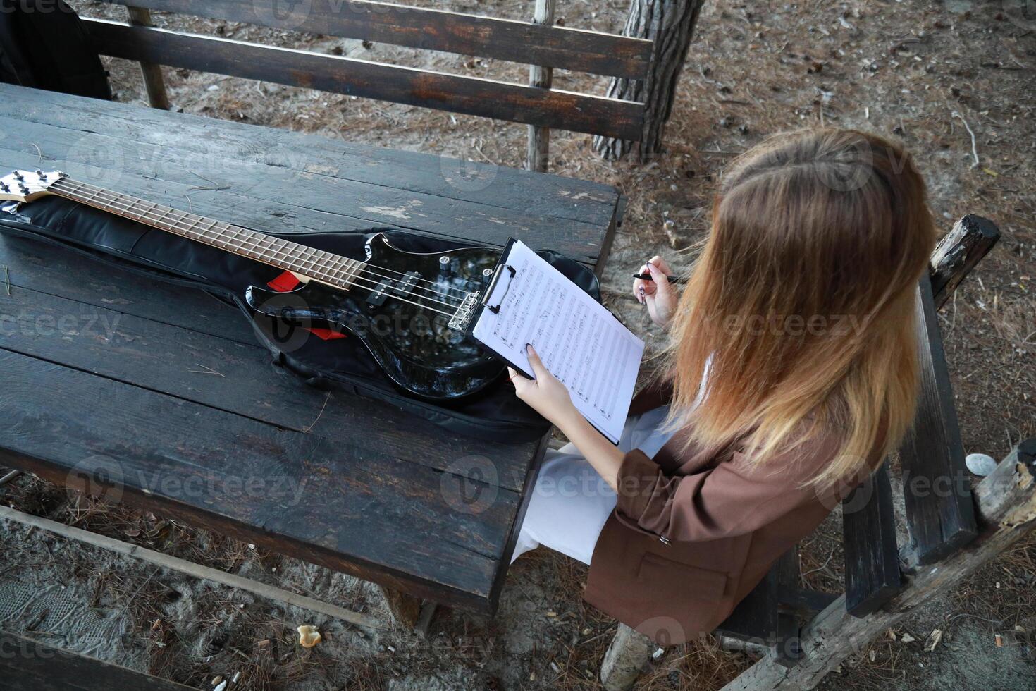 Girl Writes Music Notes On Music Sitting At The Park Table In The Nature Outdoor photo
