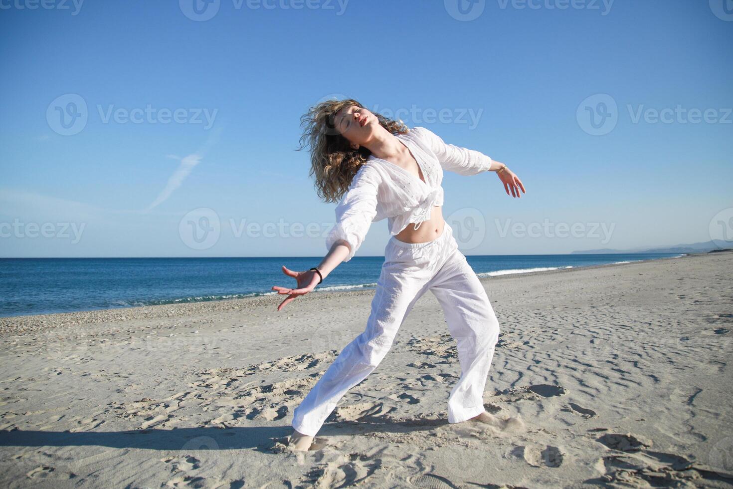Pose Of Young Woman Dances On Sicily Beach In Summer Vacation With White Shirt photo