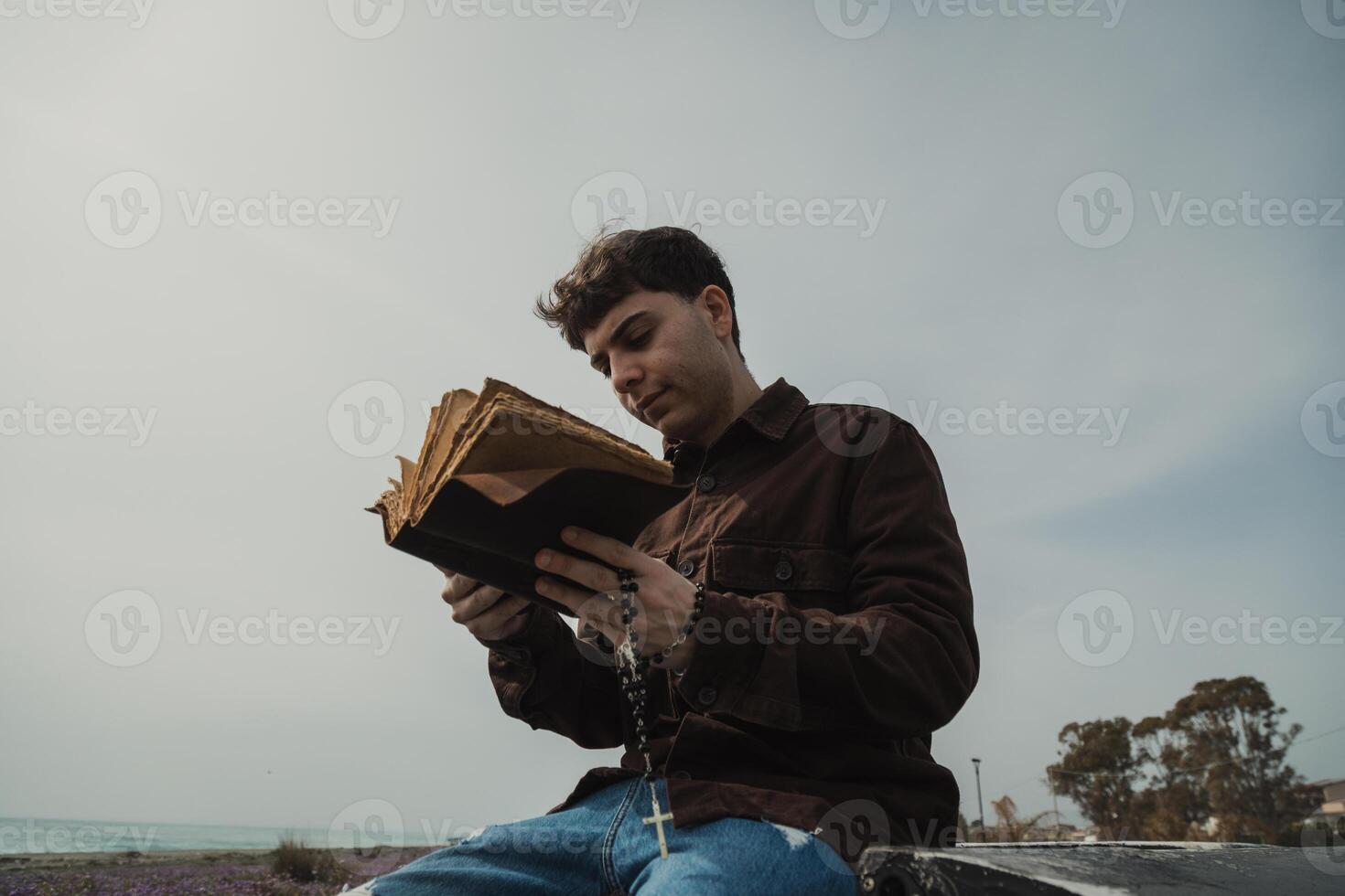 Christian Man Reading A Prayer On The Bible Book While On The Beach Outdoor photo