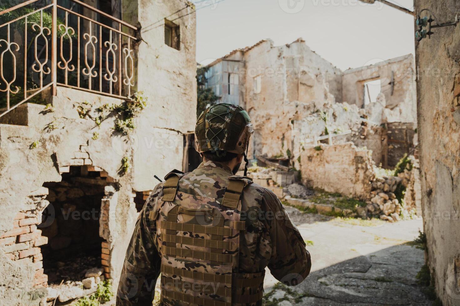 Soldier In Uniform Checks The Walls Of Destroyed Houses In The Village photo