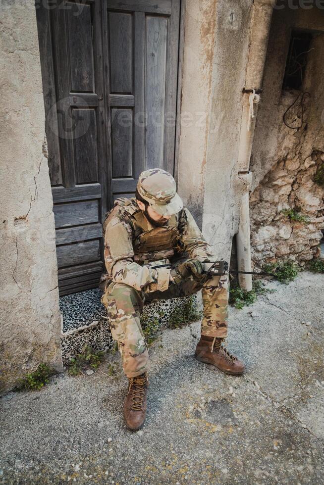 Soldier Sitting Near A Ruin Communicates With His Team photo