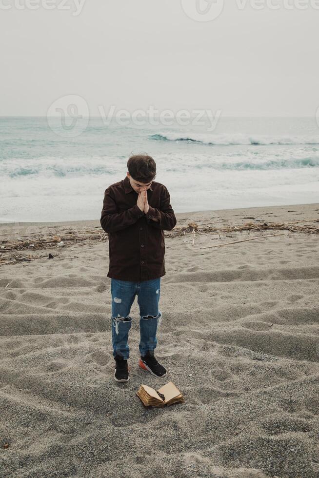 Man Flipping The Pages Of The Bible Book While Praying By The Ocean photo