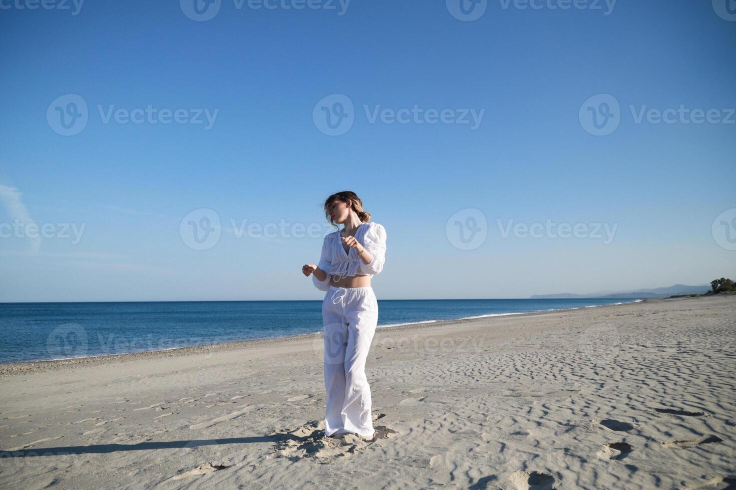 elegant Girl With White Dress Dances On The Beach In Summer Near The Sea photo