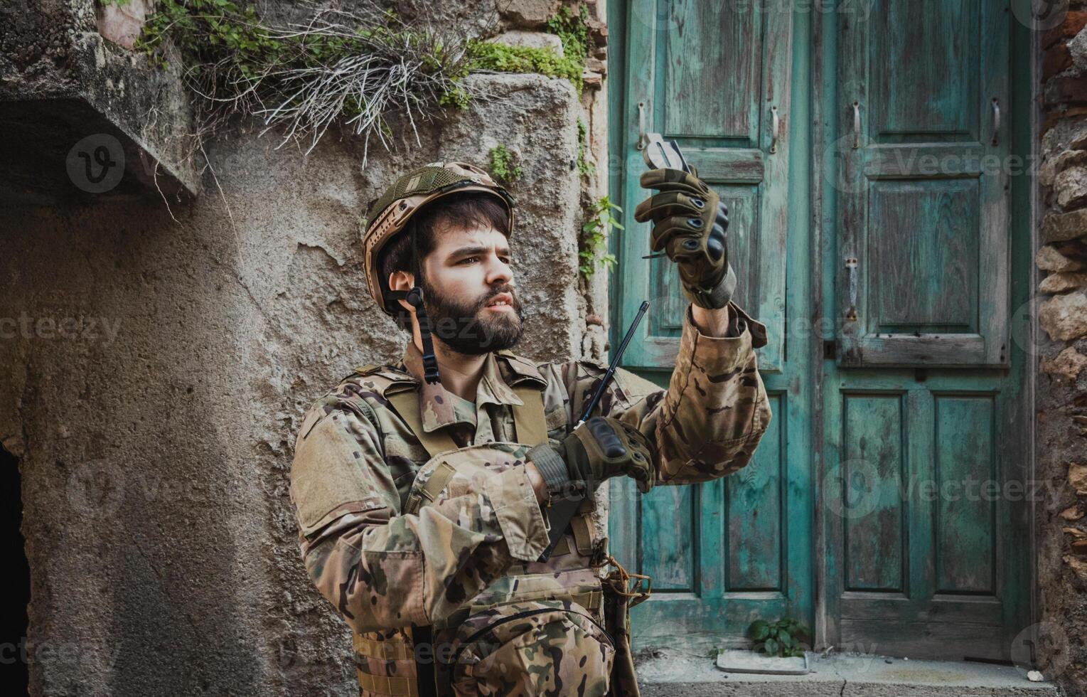 Soldier Sitting Near A Destroyed House Checks His Compass photo