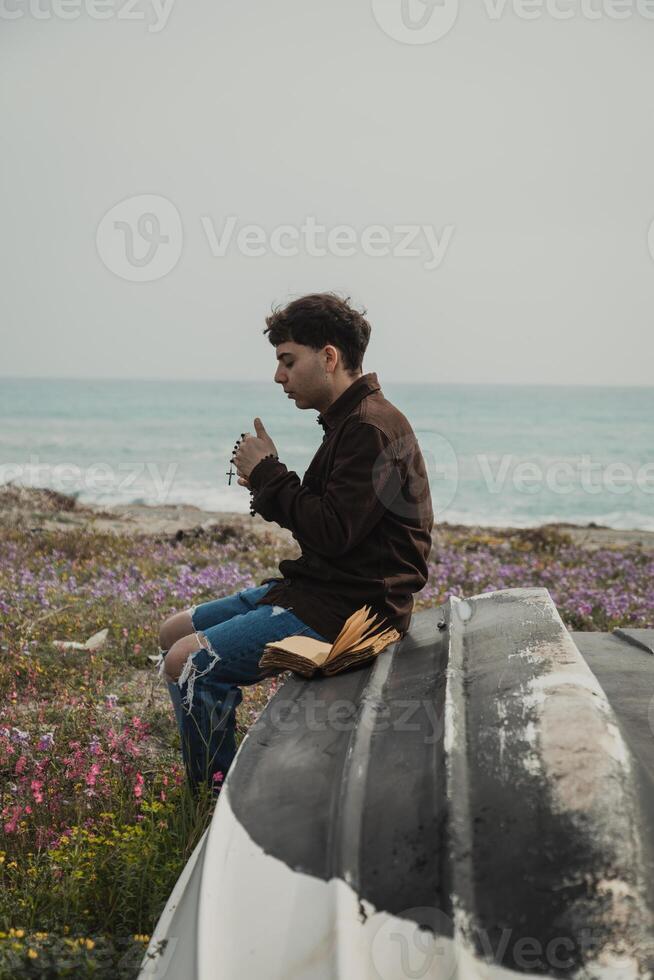 Religious Boy Reading A Prayer On The Bible Book While On The Beach photo