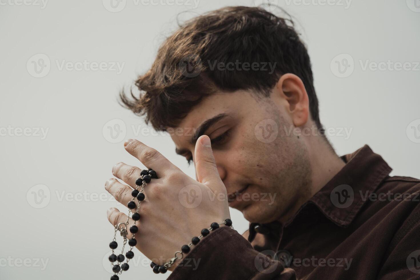 Man Praying With A Rosary And Eyes Closed On The Shore photo